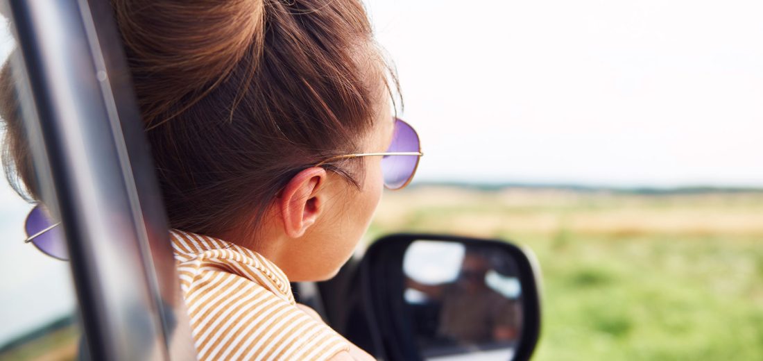 Een vrouw met een zonnebril kijkt uit het raam van een auto tijdens de rit naar Medisch Centrum Gorecht in Hoogezand.